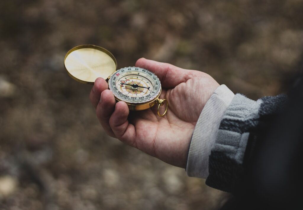 man holding campass in woods